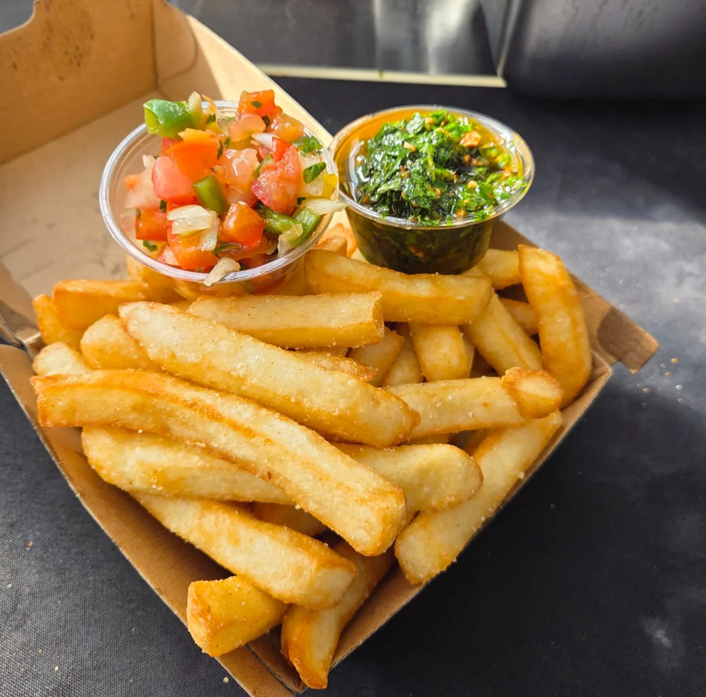 Golden crispy chips served with fresh chimichurri sauce at a Sydney street food event